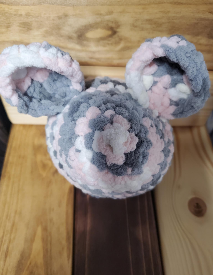 Crochet mouse toy with gray and pink on a wooden surface
