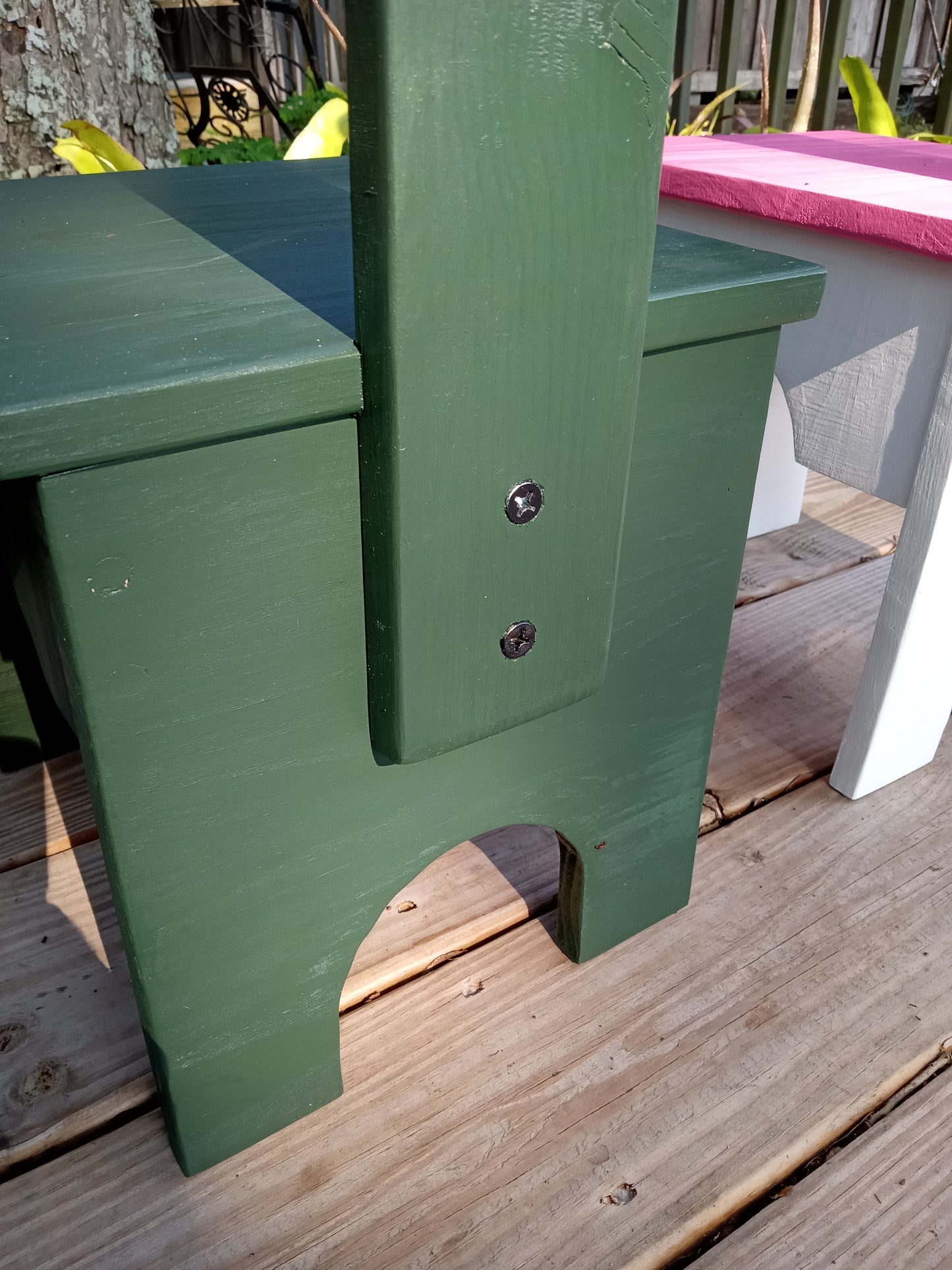 Close-up of a green Sturdy step stool on a wooden deck showing the bolts holding the handle in place.