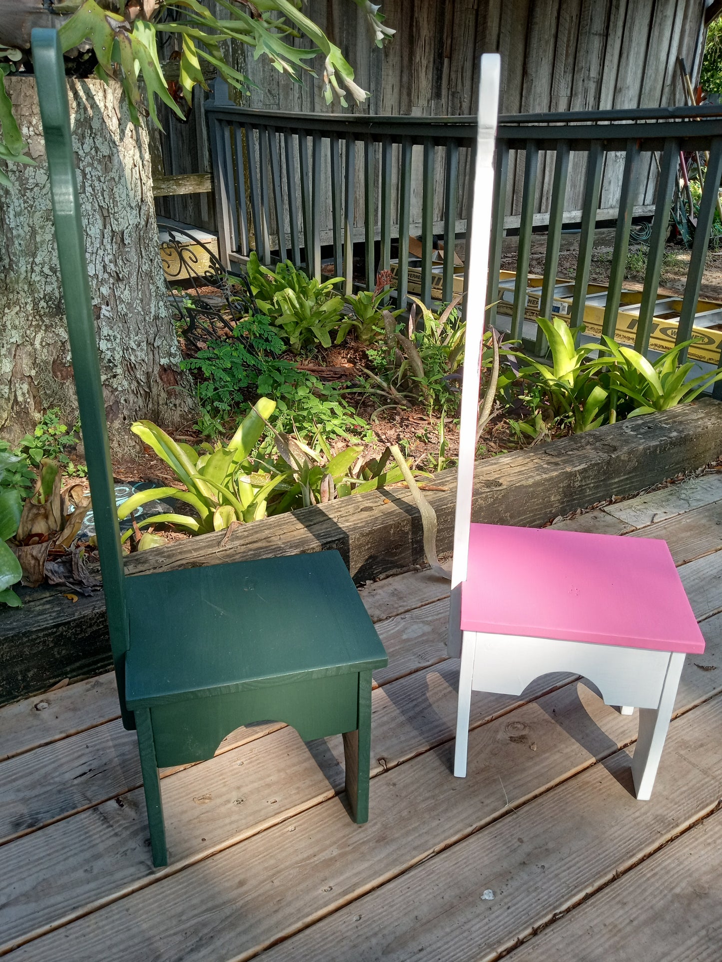 Colorful Stable step stools standing sideways on a wooden deck with plants in the background.