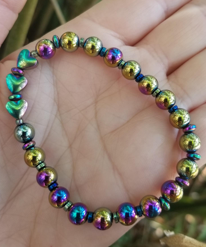 A multicolored beaded bracelet with round and rondelle beads, featuring metallic and rainbow hues, held in a person's hand.