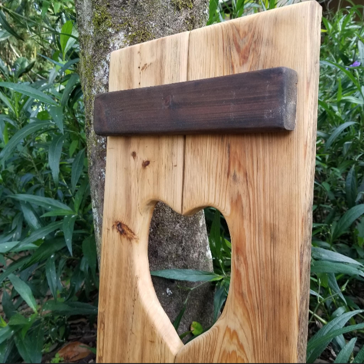 Cypress Wall Decor Coat Rack with heart cutout and horizontal strip, leaning against a tree, showcasing rustic design for hanging coats.