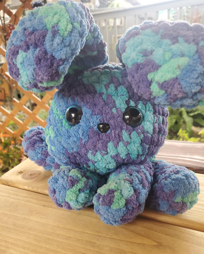 Crochet bunny toy with blue and purple pattern on a wooden surface