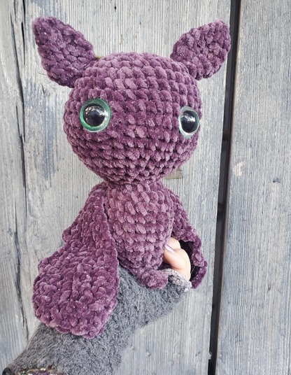Purple crochet bat with large eyes on a wooden background