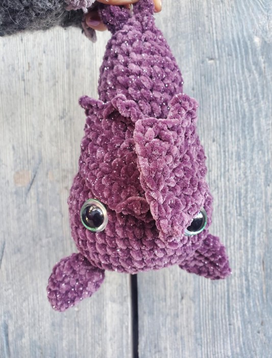 Purple plush bat toy on a wooden surface