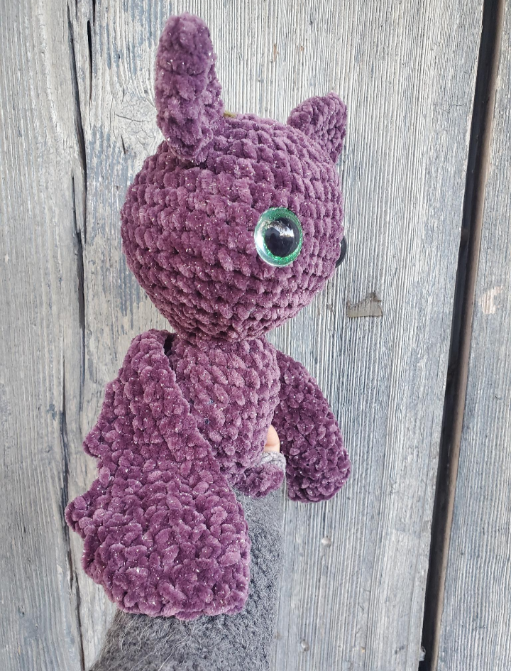 Purple crochet plush bat on a wooden surface