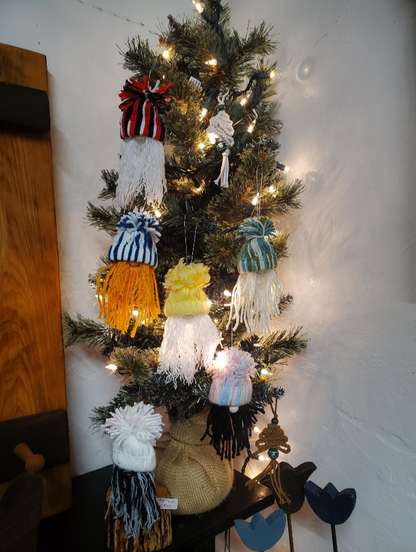 Decorative Christmas tree with colorful gnome ornaments against a white wall.