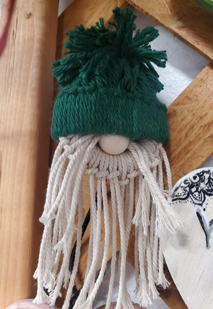 Knitted gnome with a green hat and white beard on a wooden surface