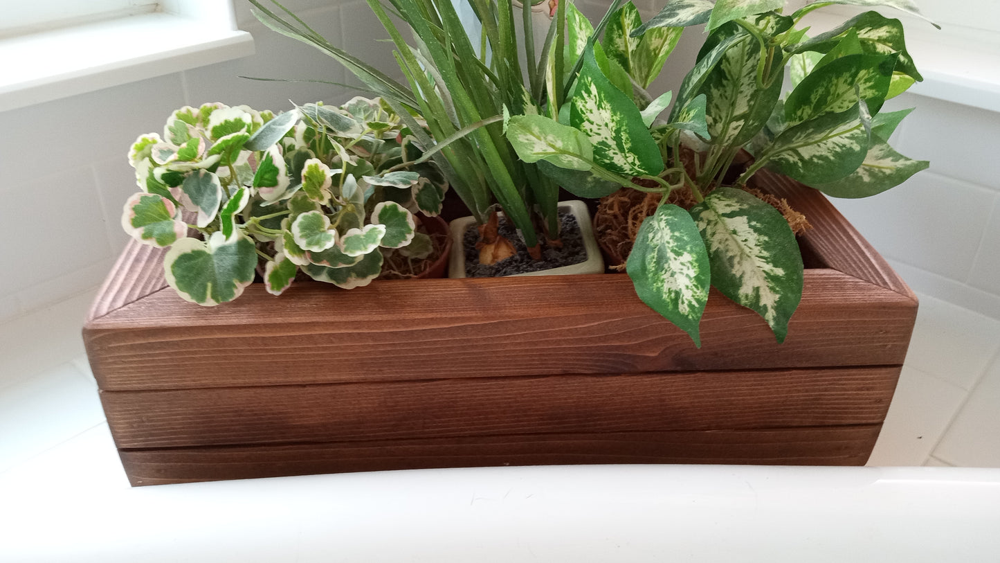 Large Cedar Planter Box on bathtub ledge, holding three pots with variegated houseplants. Handcrafted cedar, mitered corners, perfect for displaying foliage.