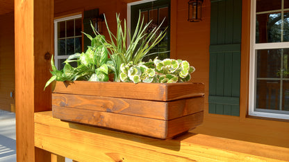 Large Cedar Planter Box on a porch railing, filled with varied green foliage, showcasing handcrafted cedar construction with mitered corners for strength.