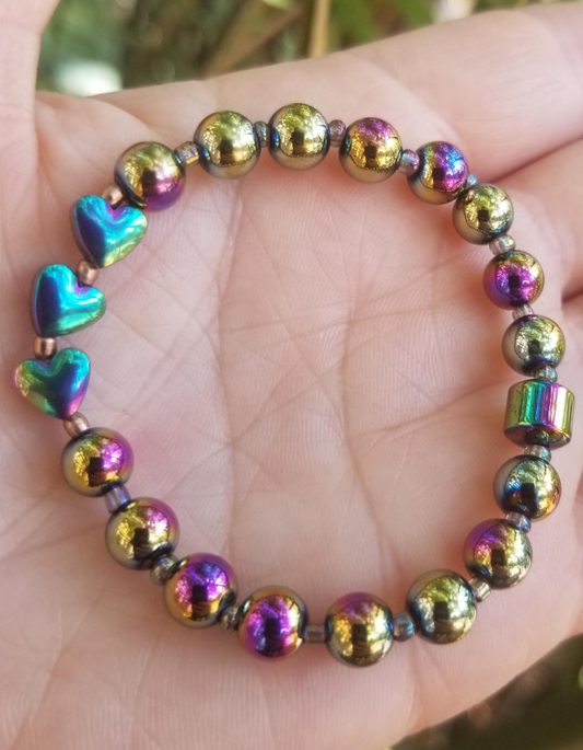 A multicolored beaded bracelet with heart-shaped and round beads, held in a person's hand.
