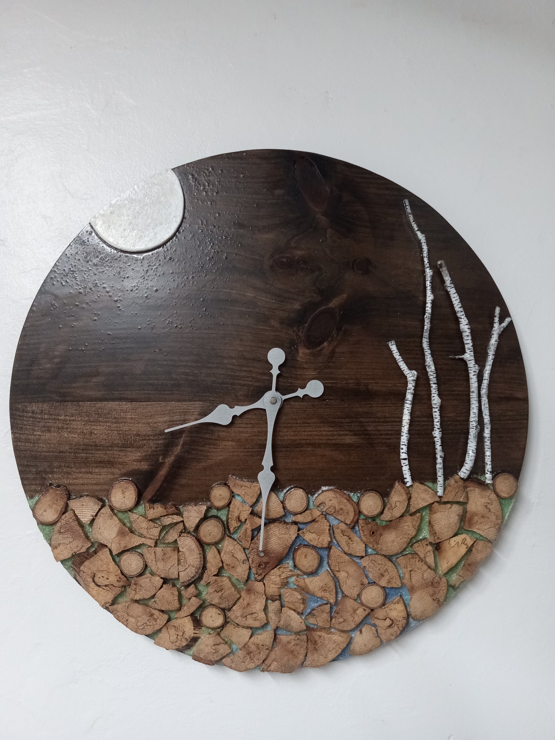 Round wooden wall clock with nature-themed design on a white background.
