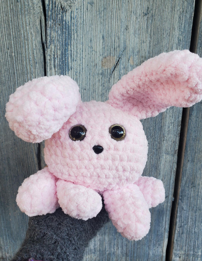 Pink crochet bunny toy against a wooden background