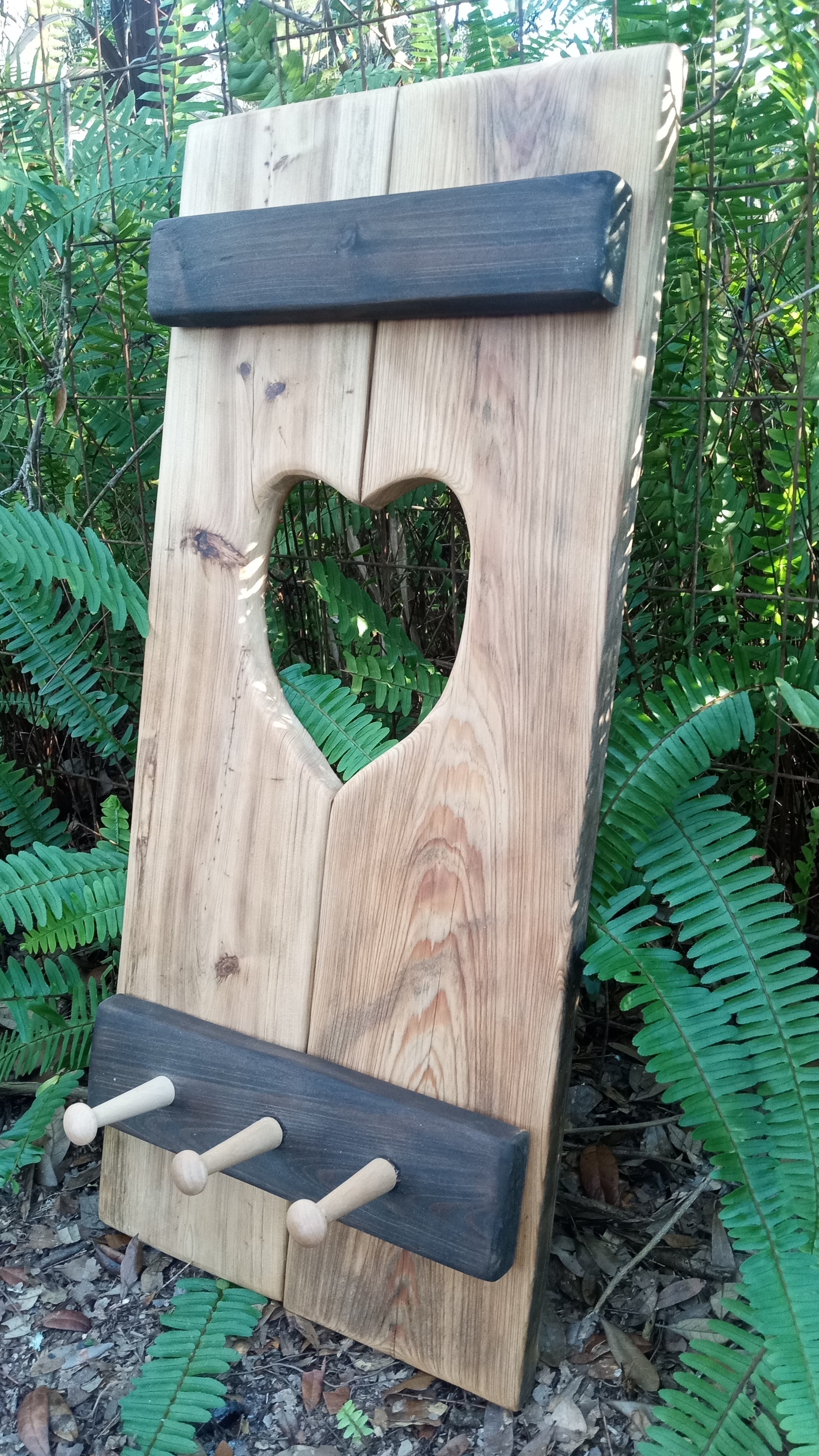 Cypress Wall Decor Coat Rack features a vertical wooden plank with a heart cutout, two crossboards, and three pegs, ideal for hanging coats.