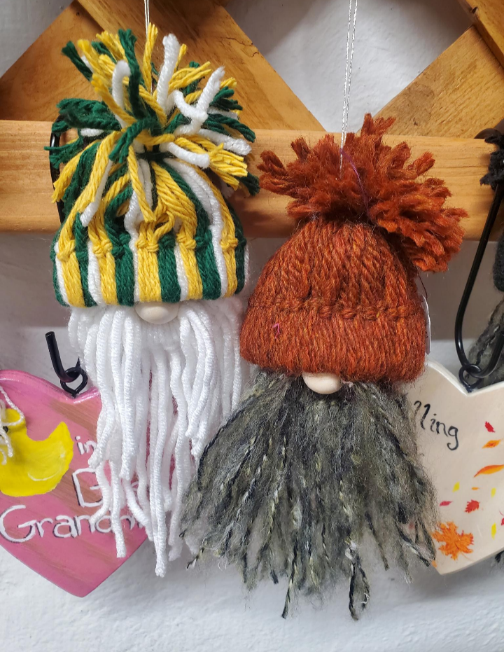 Two knitted gnomes with colorful hats on a wooden surface.