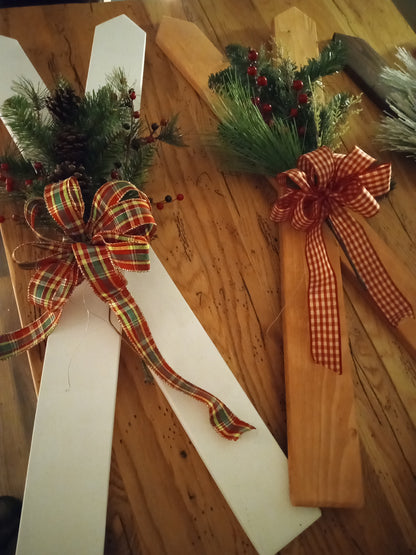 Decorative wooden skis with ribbons and festive winter floral bouquet on a wooden surface