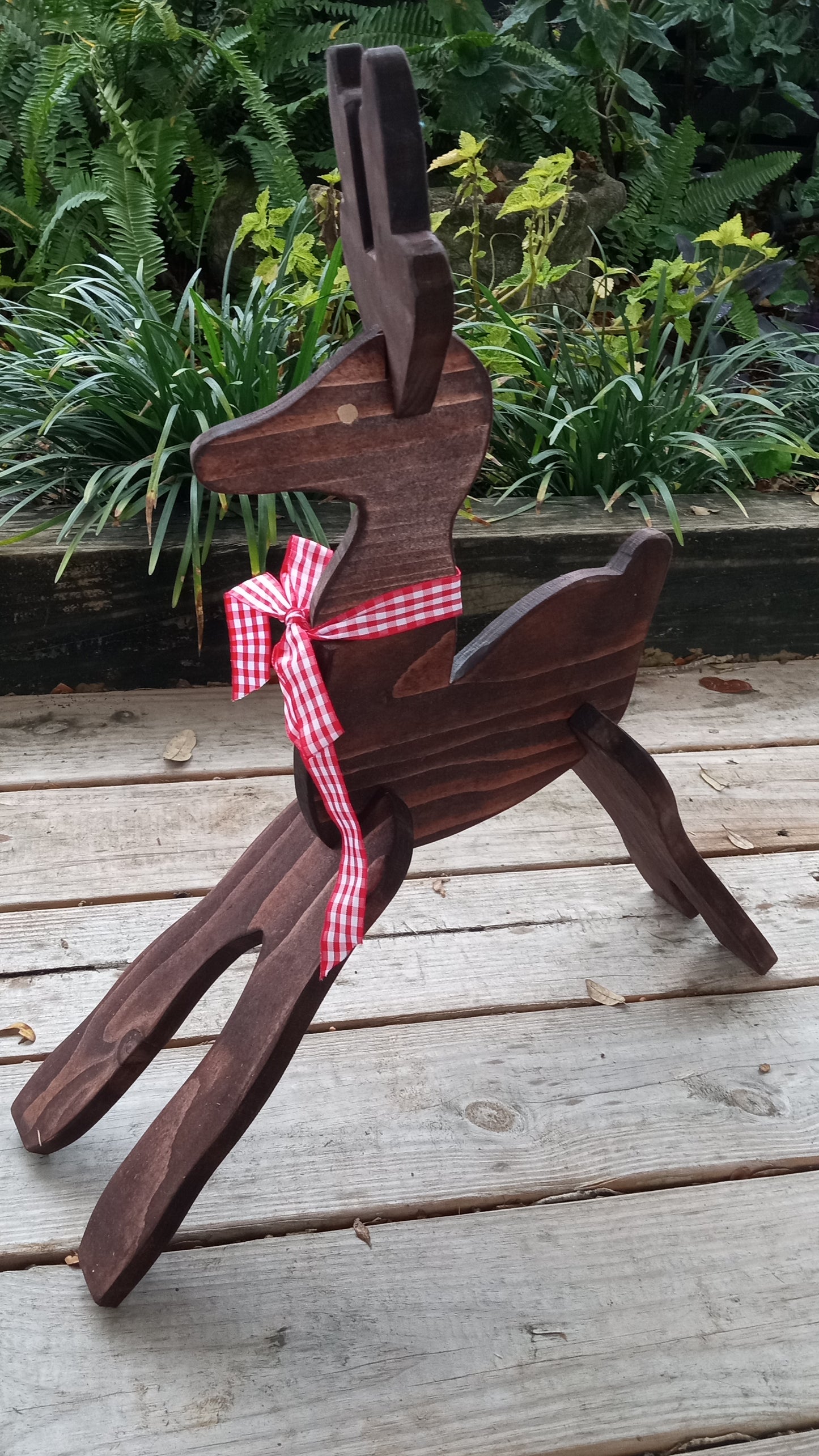 Wooden reindeer with a red and white checkered ribbon on a wooden surface.