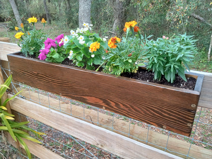 Hanging Fence Planters made of stained wood, filled with marigolds, petunias, begonias, and a leafy perennial, mounted on a wood-and-wire fence panel.